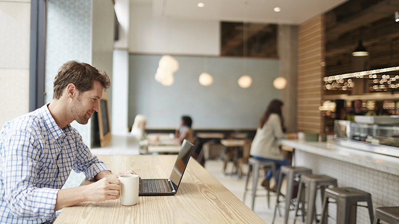 Man on laptop holding coffee mug