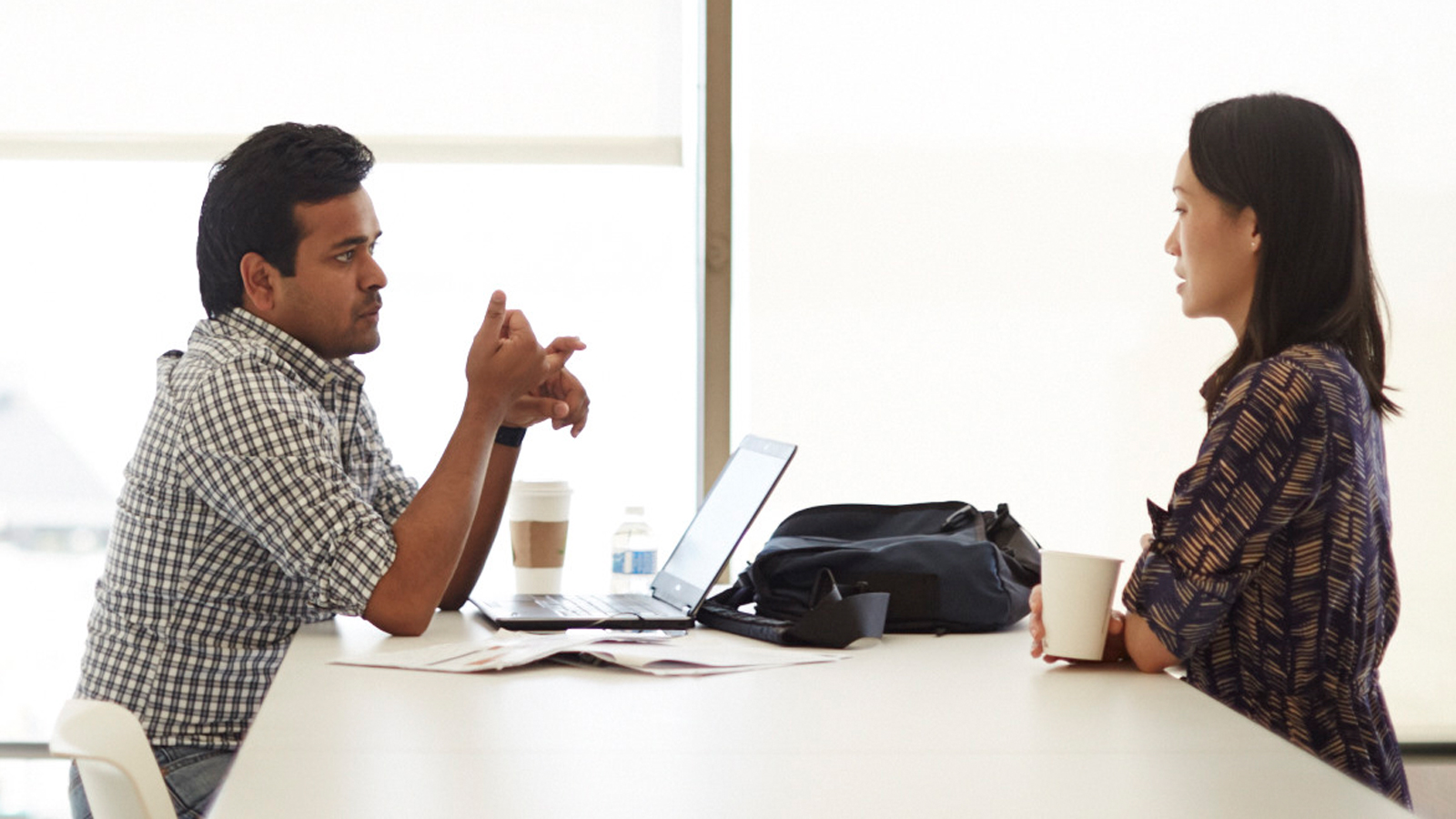 office-manwoman-table-1600x900 A man and a woman sitting at a table and having a conversation.