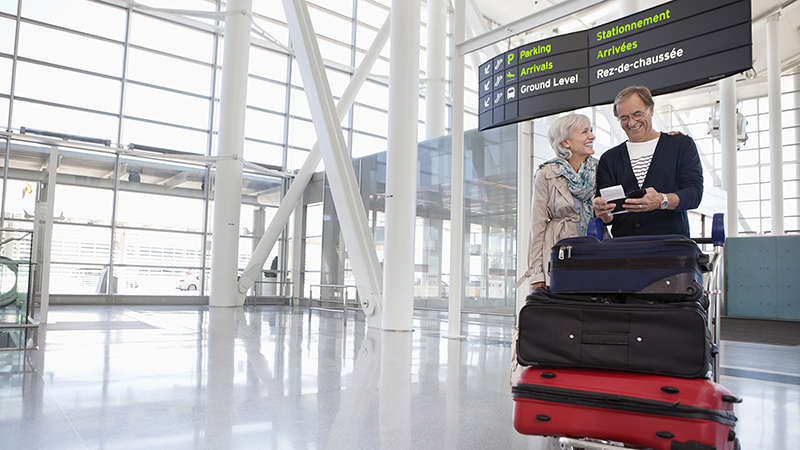 Супружеская пара с багажом в аэропорту Smiling couple with full luggage trolley in airport.
